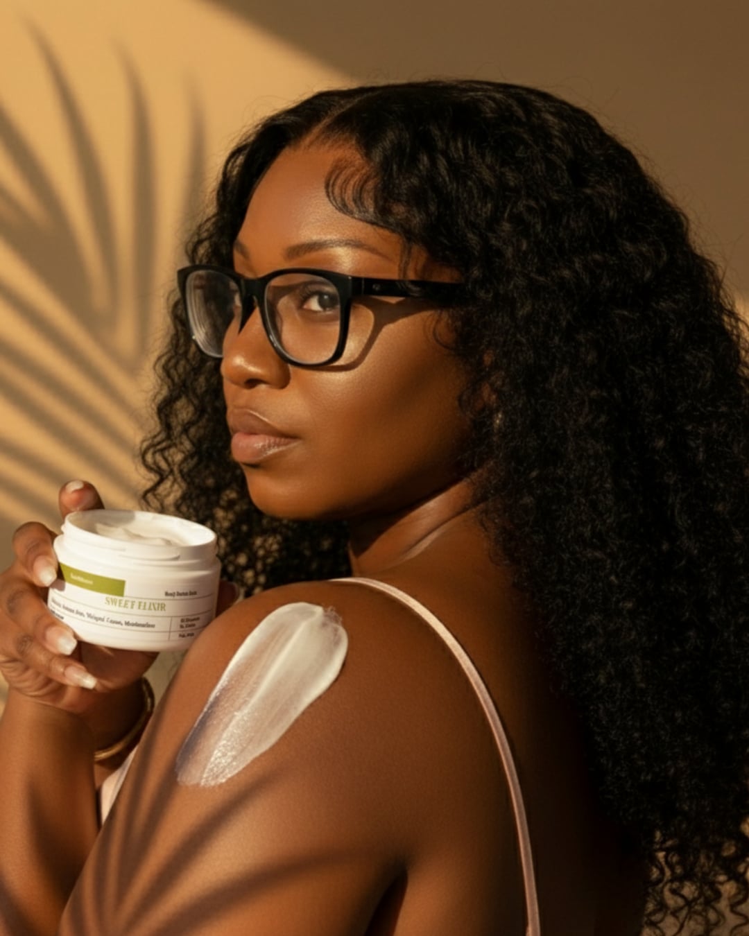 Woman applying a jar of cream to her shoulder with a palm leaf shadow in the background