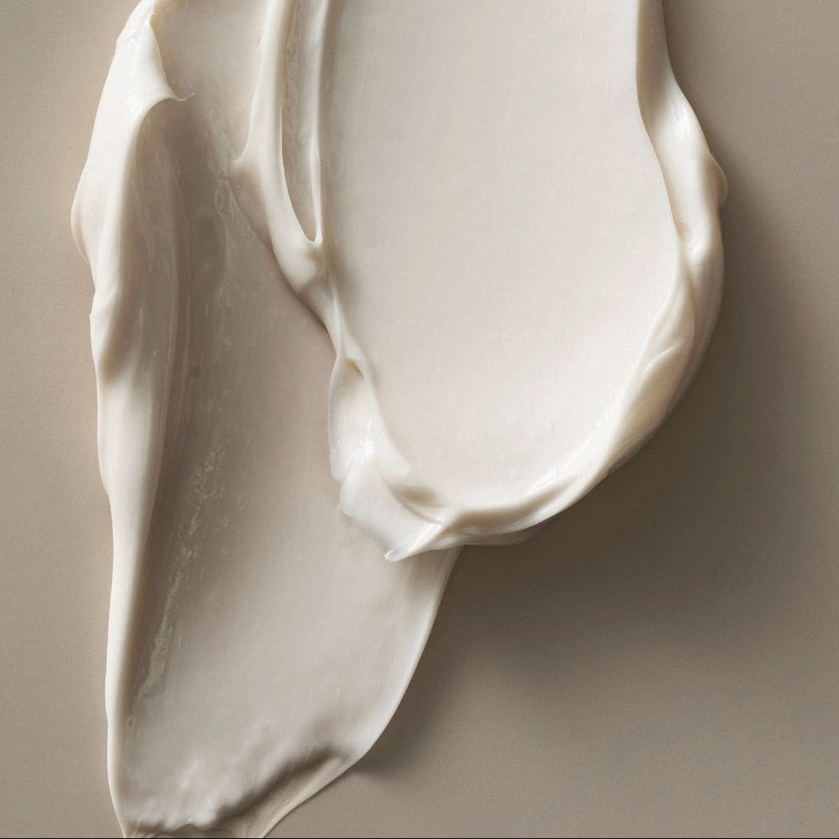 Close-up of smooth, white cream on a beige background